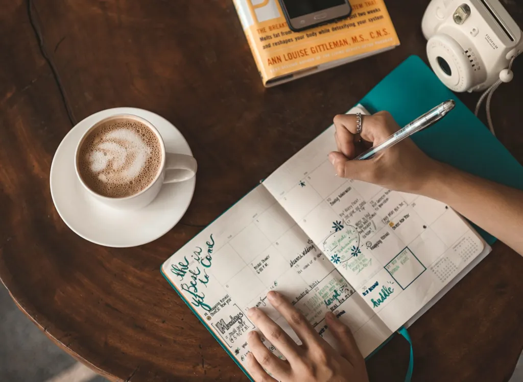 Woman writing in a gratitude journal with a cup of coffee as part of a mindful routine