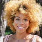 Confident young woman smiling while standing outdoors in sunlight