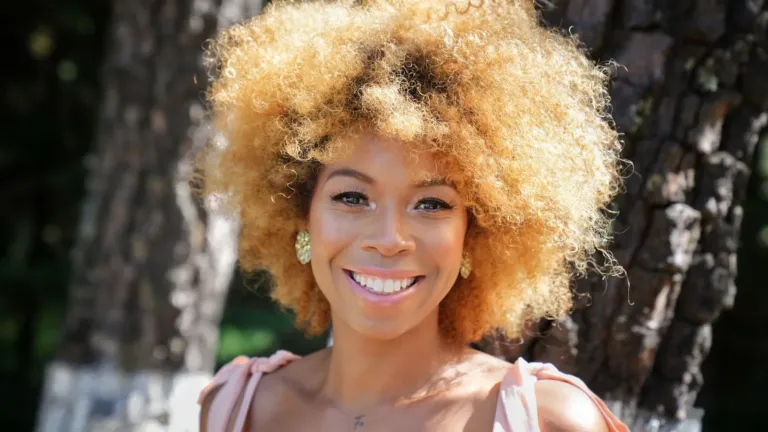 Confident young woman smiling while standing outdoors in sunlight