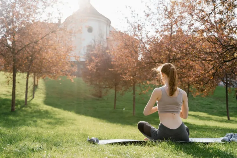 Person sitting calmly outdoors practicing slow breathing in nature