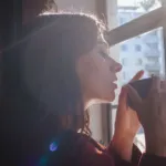 Person enjoying a calm morning with coffee by a sunlit window