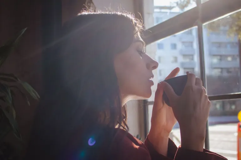 Person enjoying a calm morning with coffee by a sunlit window