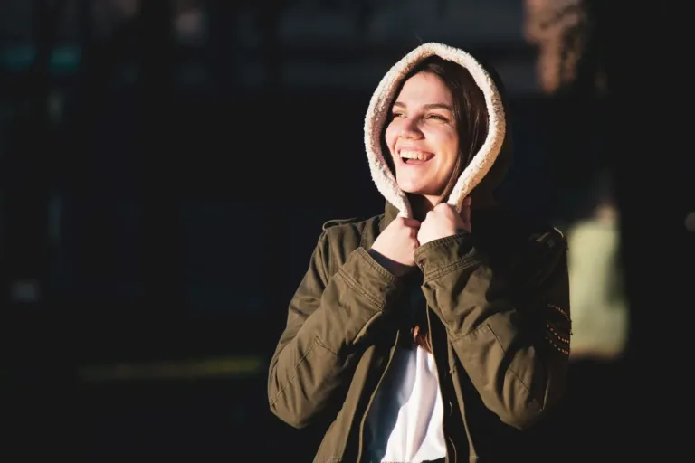 Smiling woman enjoying sunlight outdoors with a relaxed, hopeful expression